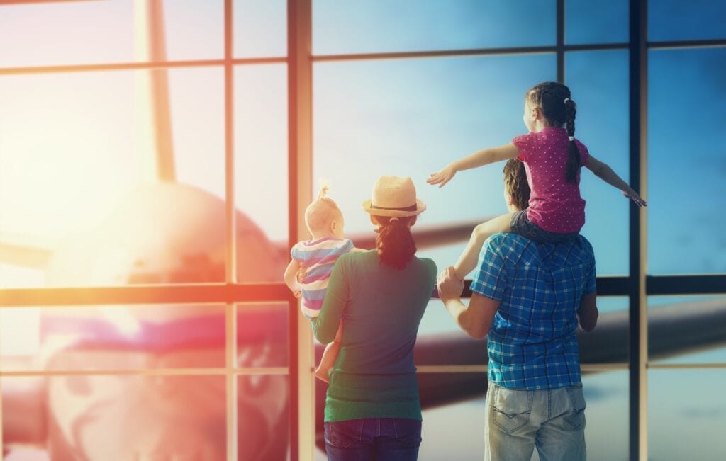 Image of a family at the airport looking at a plane through the window
